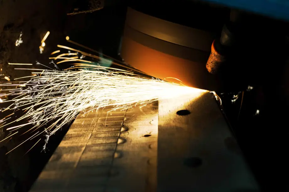 A grinding machine, grinding a sharp bevel onto a sheet of steel with sparks flying